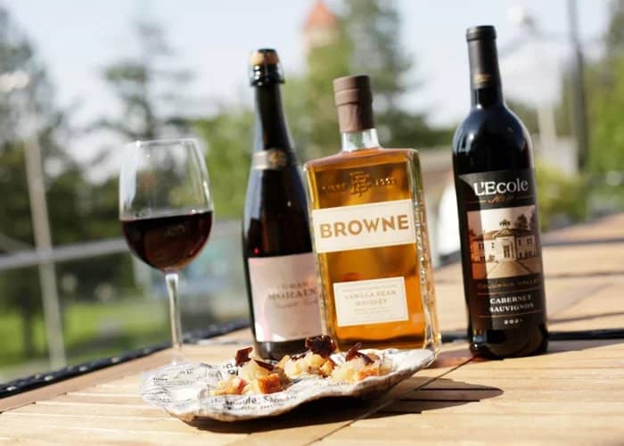 Wine bottles and a glass of red wine set outdoors at a Quad Cities tasting